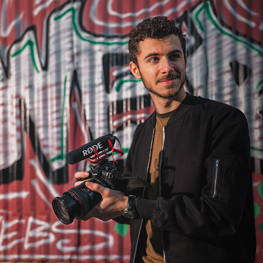 Man in front of graffiti wall holding camera with VideoMic GO