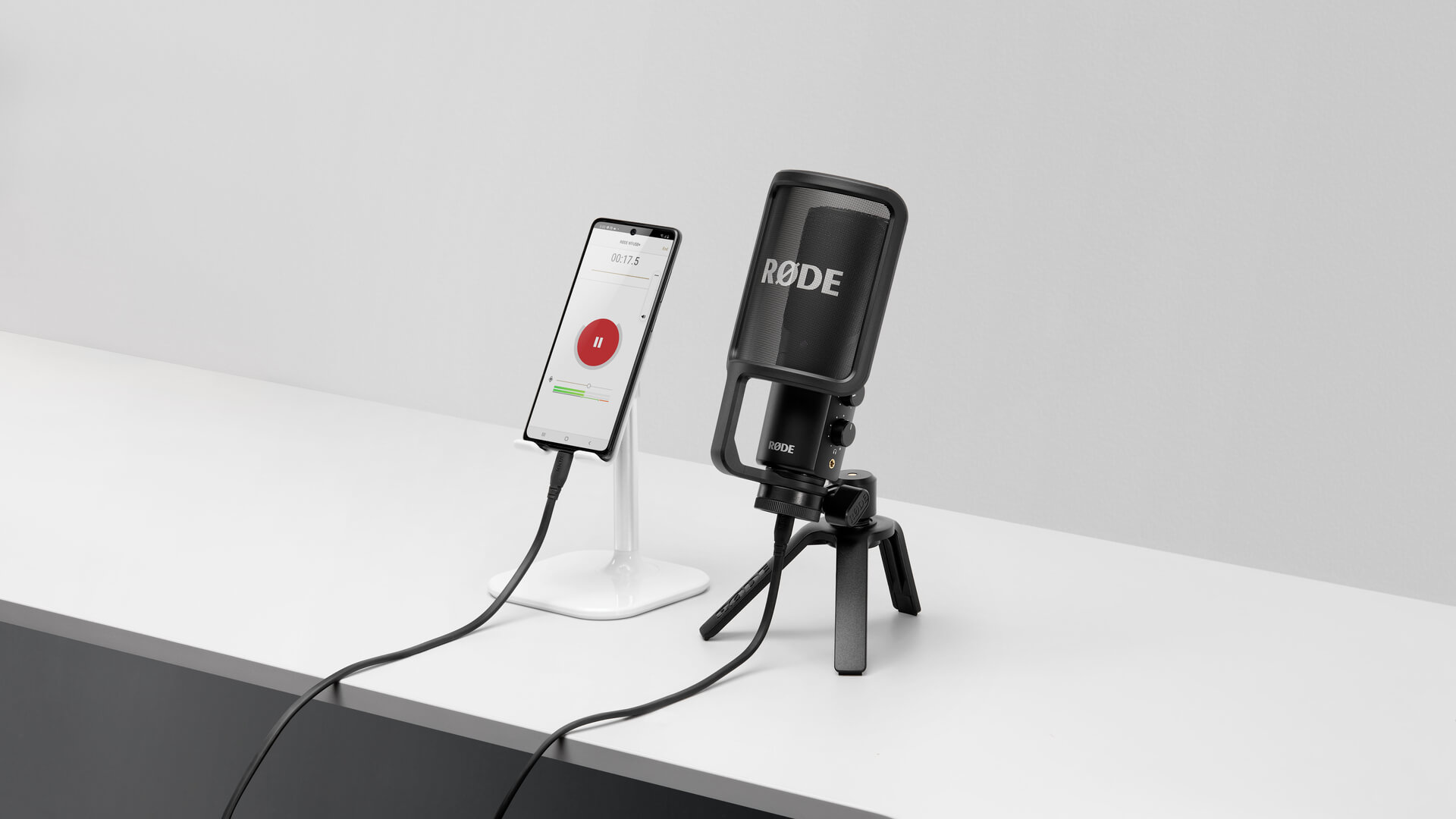 NT-USB+ on white desk connected to smartphone showing RØDE Reporter